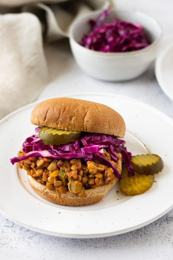 sloppy joe on a bun with pickles and cabbage