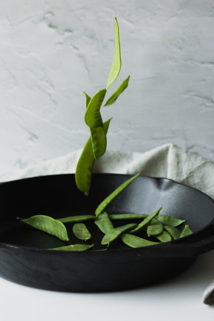snow peas falling into a cast iron pan
