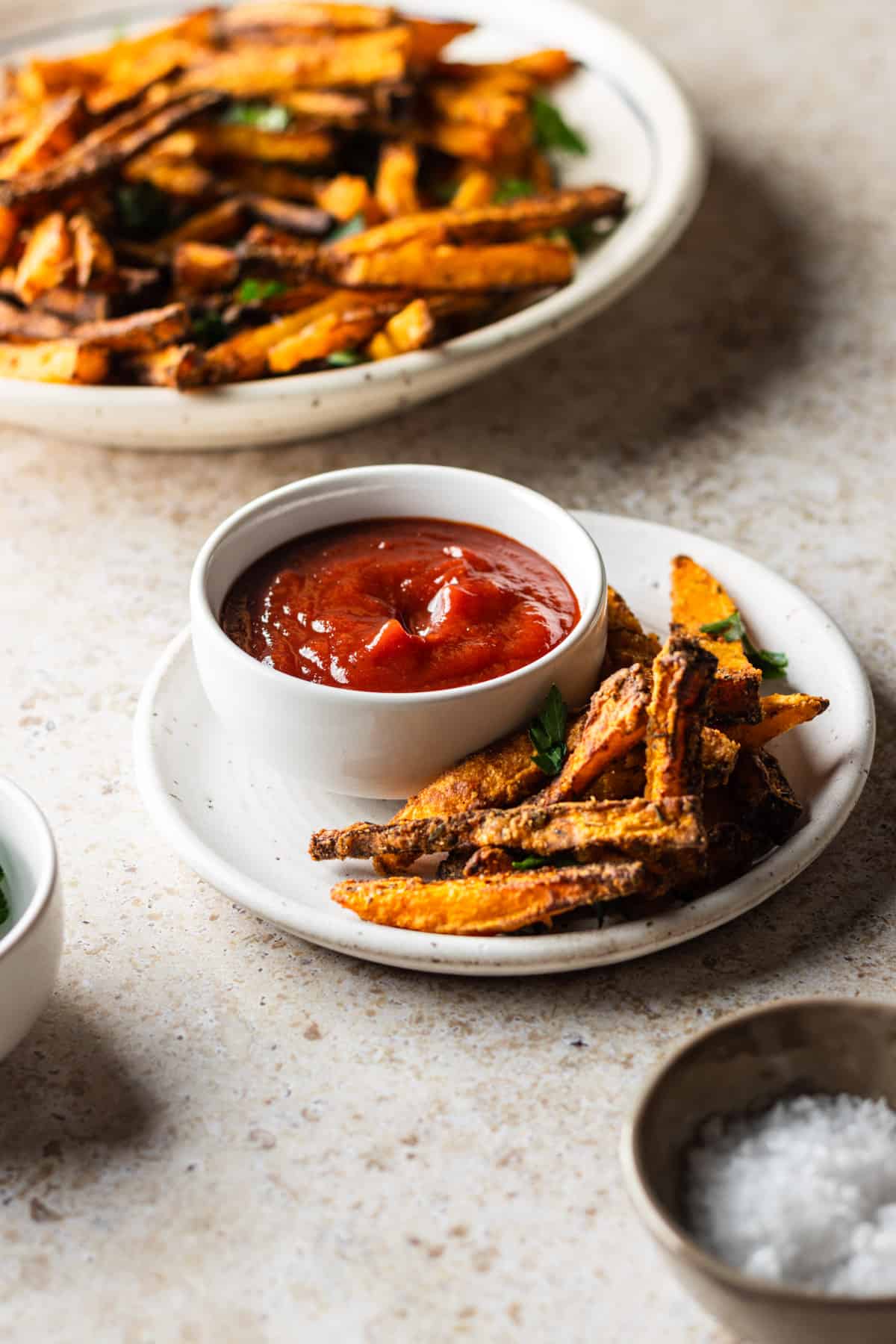 A small plate with air fried butternut squash fries and a side of ketchup.
