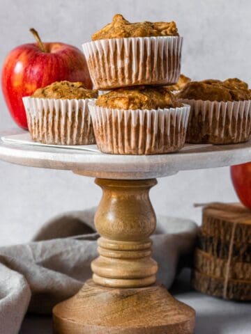 Stack of muffins with apples on a cake stand.