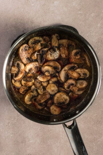 Sautéed mushroom in a sauce pan with red wine.