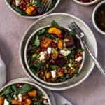 Close up of beet and butternut squash salad with forks and pomegranate seeds.