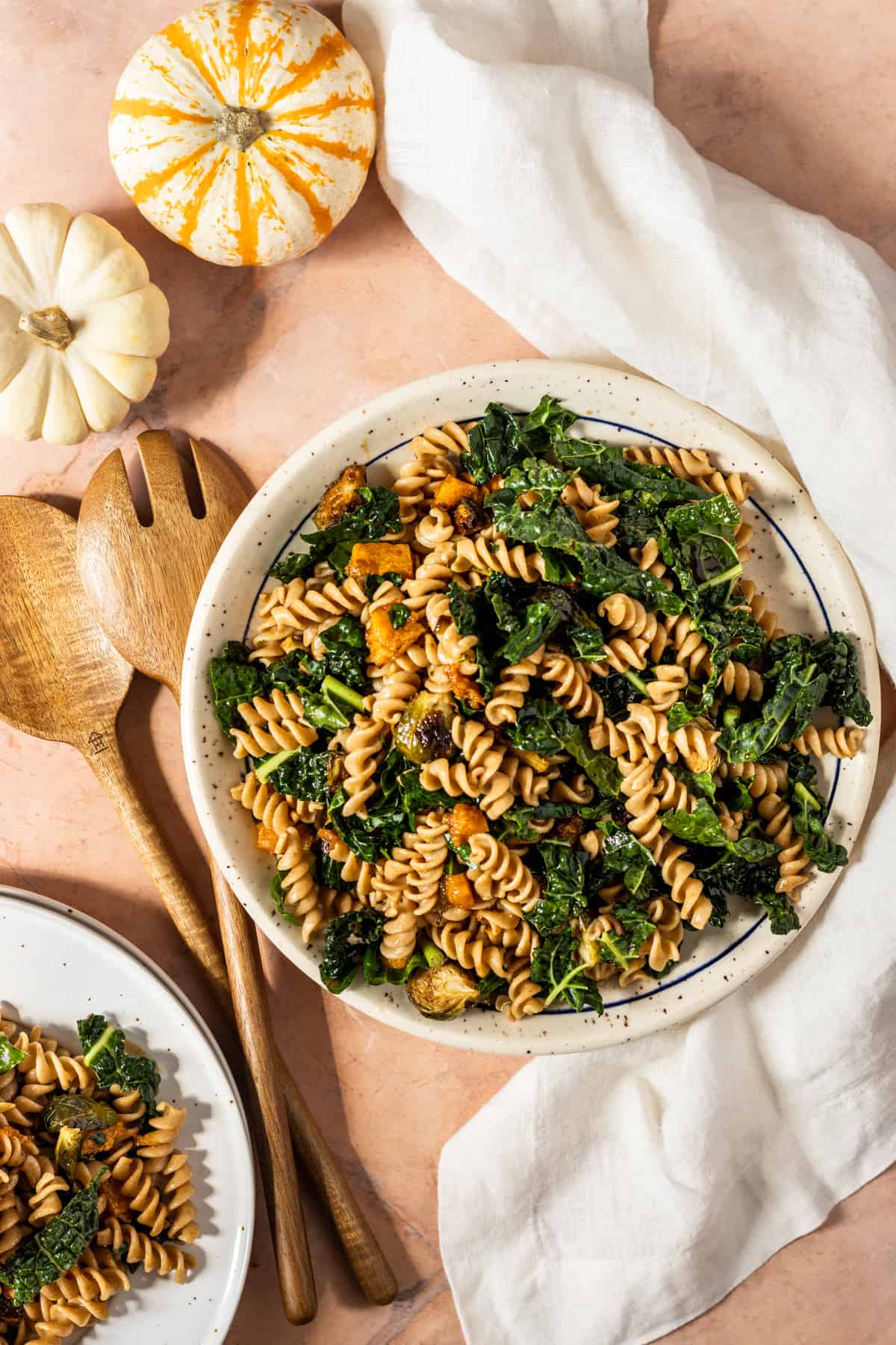 Fall harvest pasta salad on a large plate with wooden spoons and a napkin.