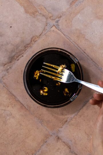 Small bowl with maple balsamic dressing being mixed with a fork.