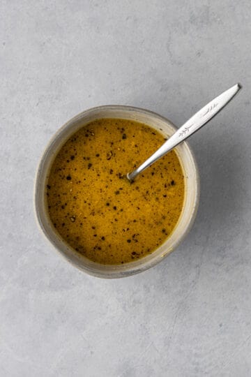 Small bowl of dressing with a fork sticking out of the bowl.