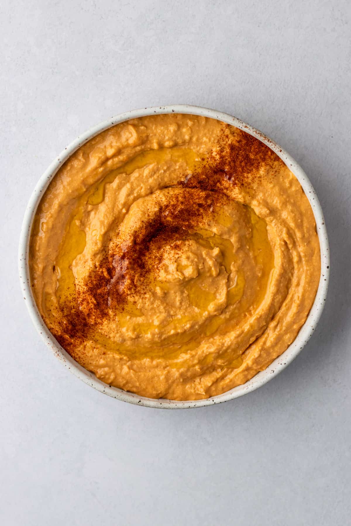 Buffalo hummus in a white bowl with a sprinkle of paprika.