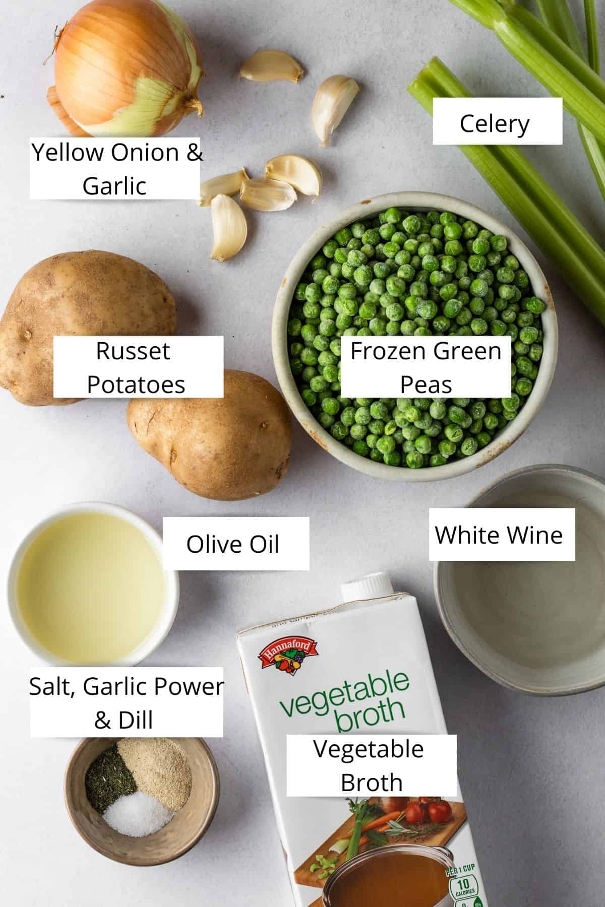 Yellow onion, garlic cloves, russet potatoes, celery, frozen green peas in a bowl, olive oil in a bowl, white wine in a bowl, spices in a pinch bowl and a box of vegetable broth.
