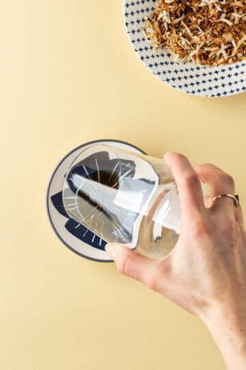 Rim of a glass being dipped into a plate of agave syrup.