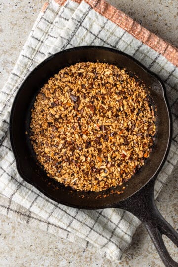 Small cast iron pan with toasted spices on a kitchen towel.