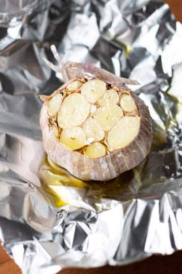One bulb of garlic on foil with the top cut off and olive oil and salt drizzled on top.