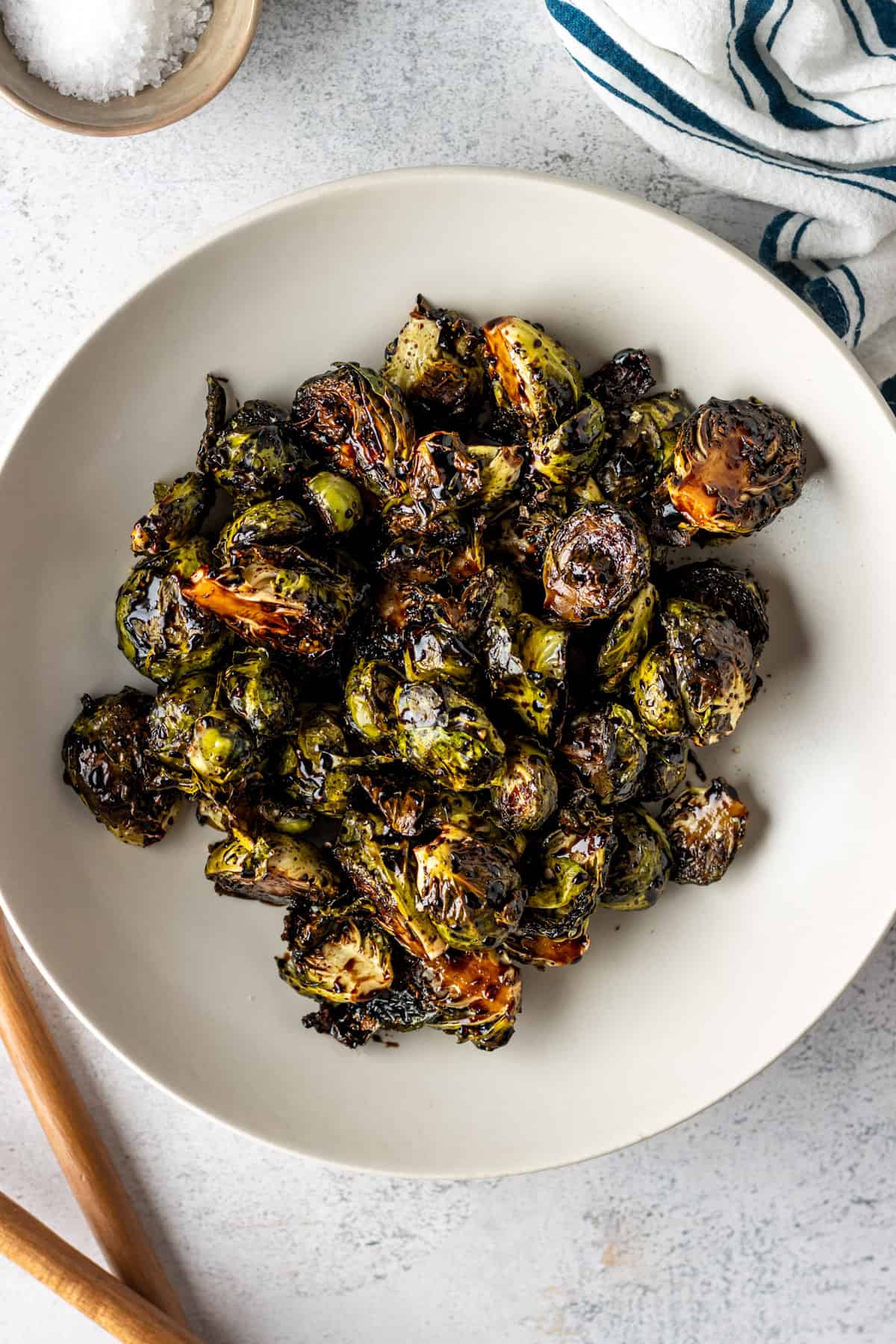 A large white bowl with cooked Brussels sprouts with balsamic glaze.