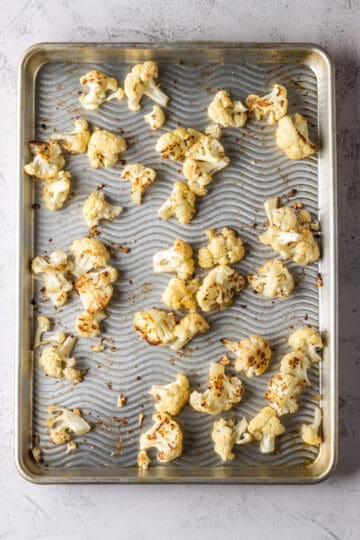 Overhead of a sheet pan with roasted cauliflower florets.
