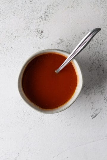 Overhead of a small grey bowl filled with hot sauce and a fork sticking out of the bowl.