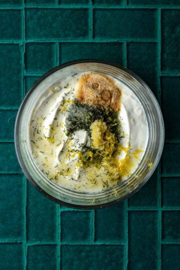 A bowl of greek yogurt with dill, garlic, lemon and garlic powder.