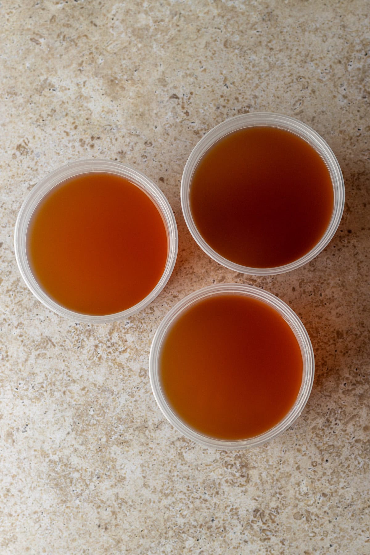 Overhead of three containers storing vegetable broth.
