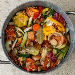 A close up of a pot with vegetable scraps and water.