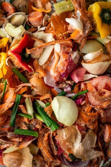 A close up of vegetable scraps including onion peels, carrot peels and peppers.