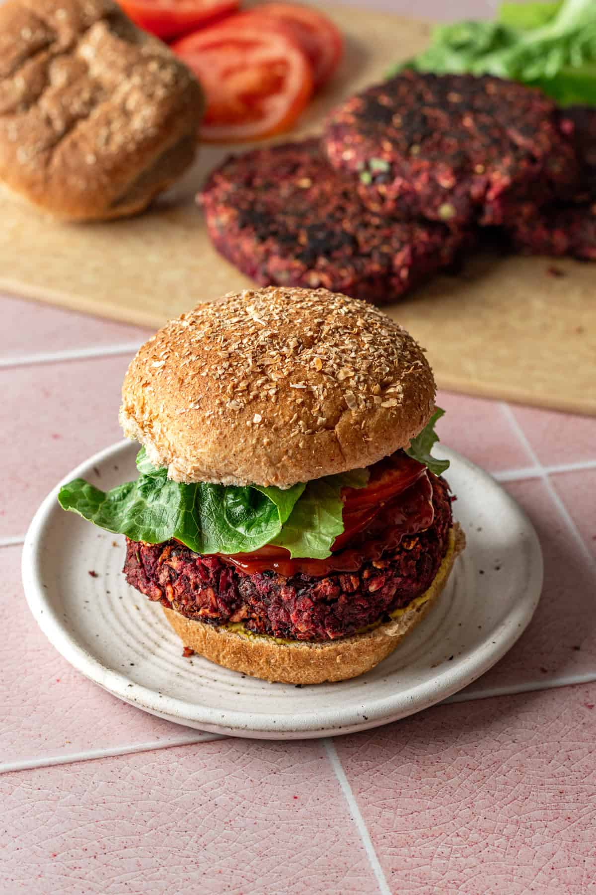 Beet black bean burger on bun with additional ingredients on the background.