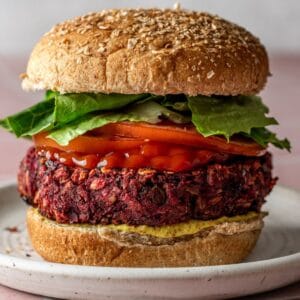 A beet black bean burger on a bun with lettuce and tomatoes.