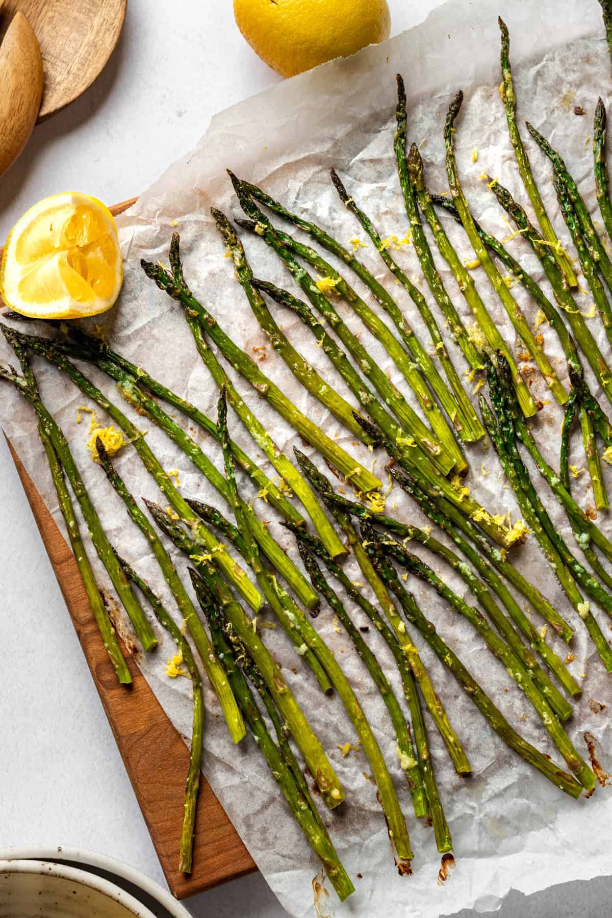 A cutting board of roasted asparagus garnished with lemons.