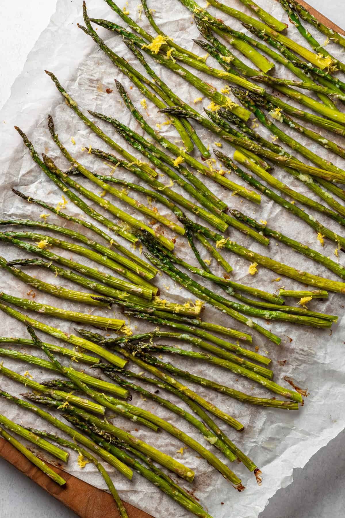 Overhead of a board of asparagus topped with lemon zest.