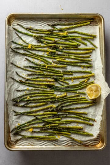 A sheet pan with roasted asparagus topped with lemon zest.