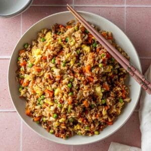 A large white bowl with fried rice with vegetables.