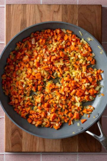 Sautéed carrots and onions in a pan.