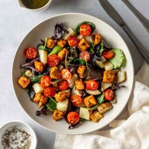 Vegan breakfast salad in a white bowl with silverware.