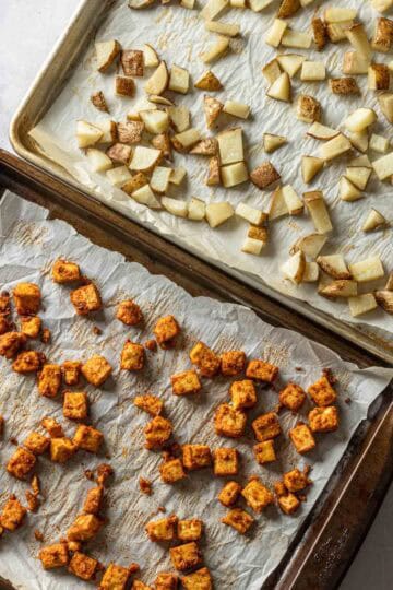 Two baking sheets with roasted potatoes and tofu.