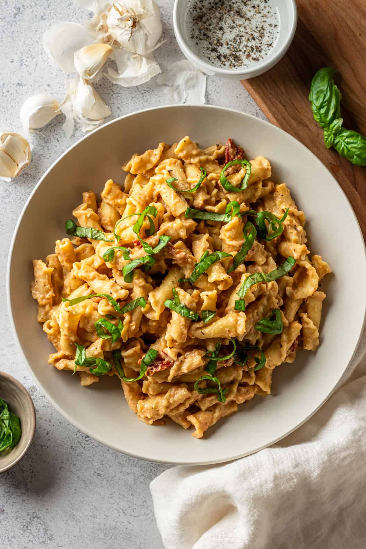 A white bowl with campanelle pasta tossed in cauliflower sun-dried tomato sauce.