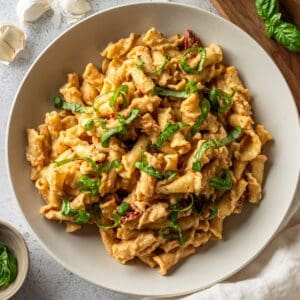 Creamy cauliflower pasta sauce tossed with pasta in a white bowl.