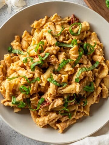 Creamy cauliflower pasta sauce tossed with pasta in a white bowl.