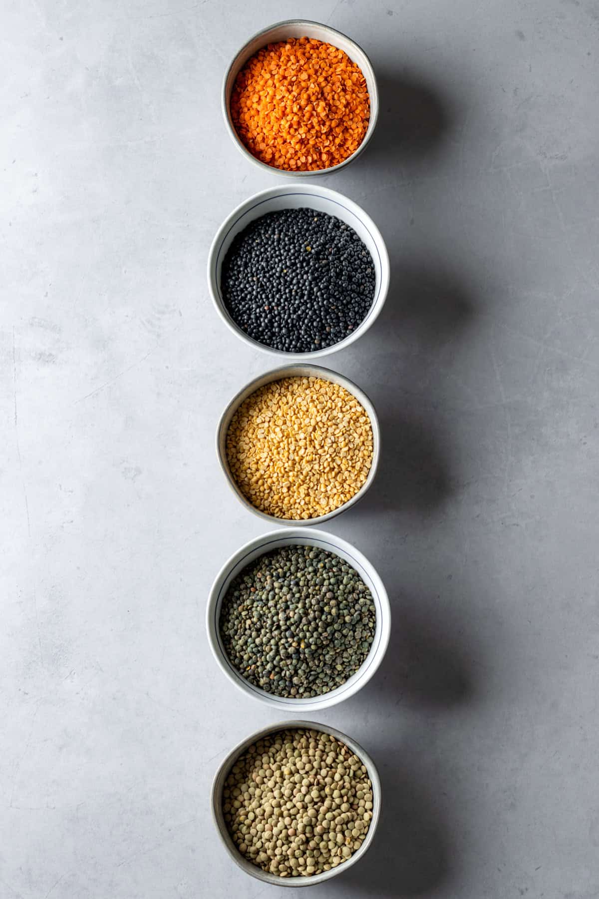 Five bowls of different lentil varieties.