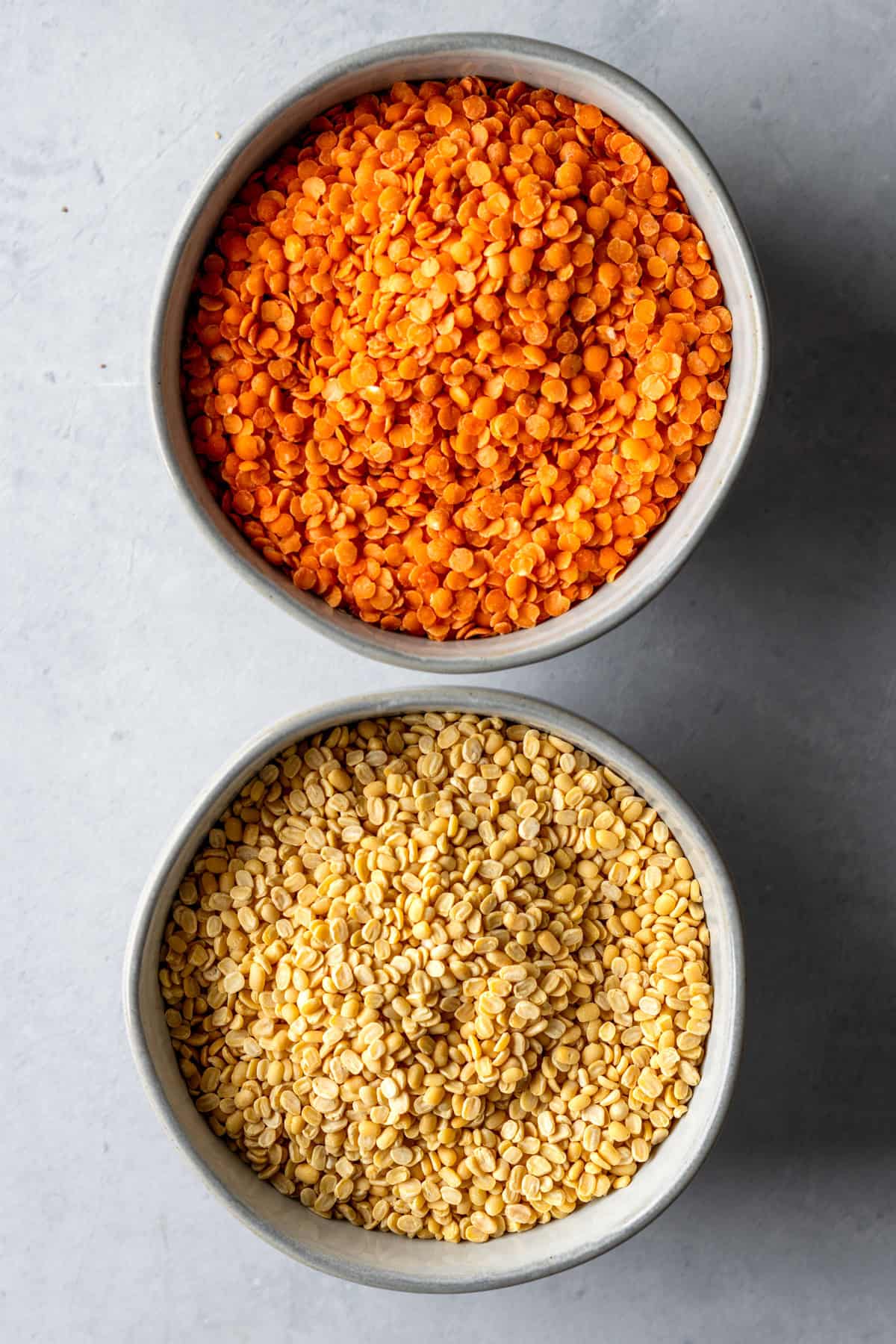 Two bowls of red and yellow lentils.