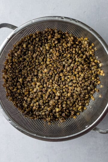 A strainer of cooked and drained lentils.