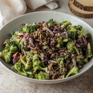 A large white bowl of lentil salad with broccoli.