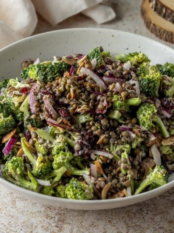 A large white bowl of lentil salad with broccoli.