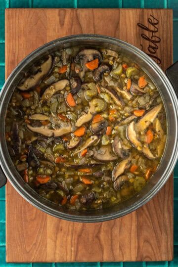 A pot of mushrooms and veggies in broth.