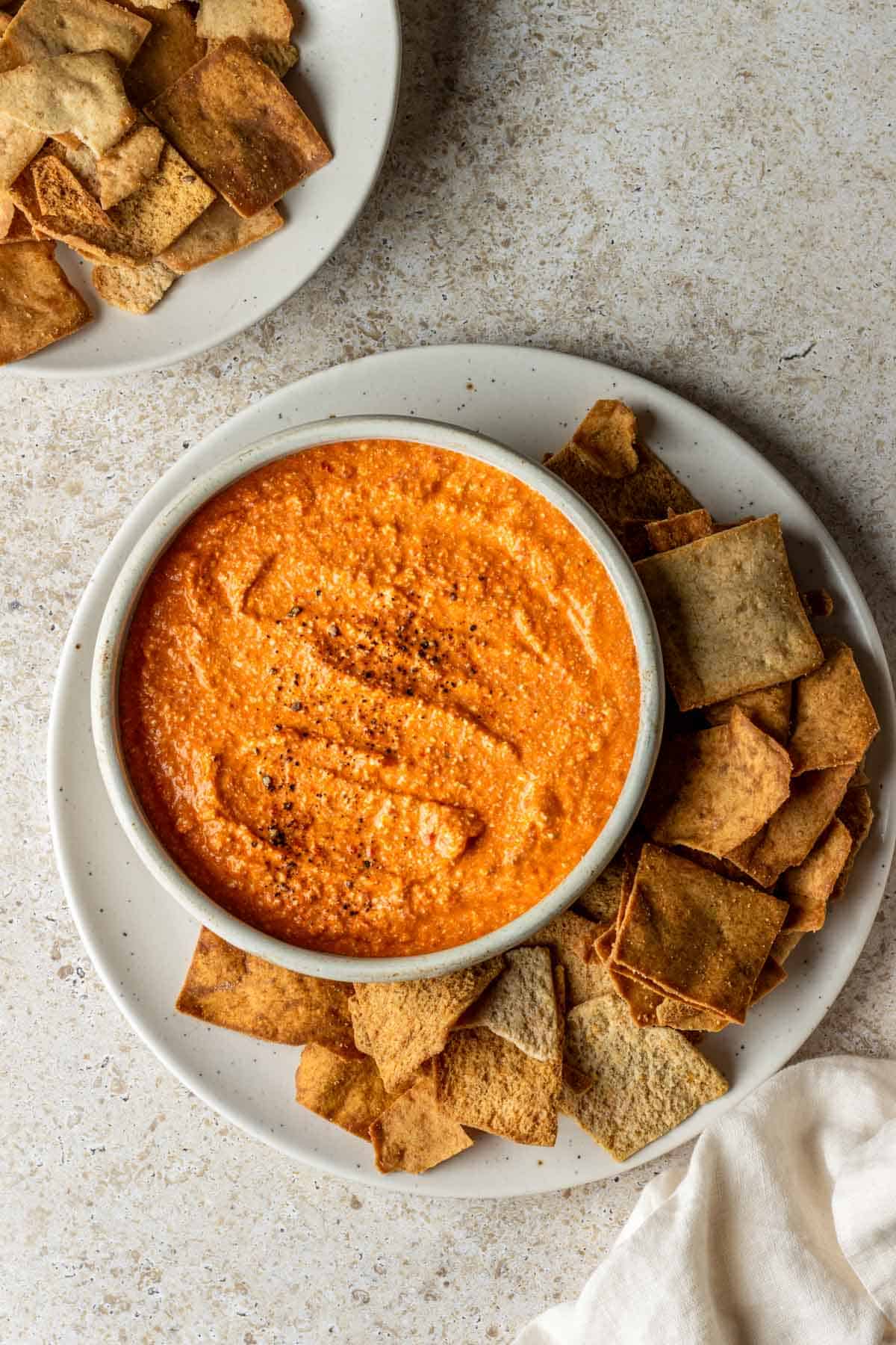 Red pepper feta dip with pita chips on the side.