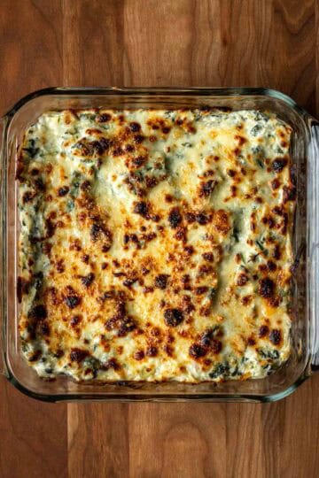 Cheesy baked spinach artichoke dip in an 8x8 dish.