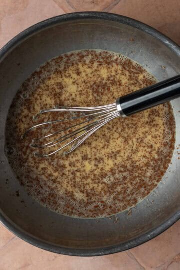 A mixing bowl of whisked eggs with cinnamon.