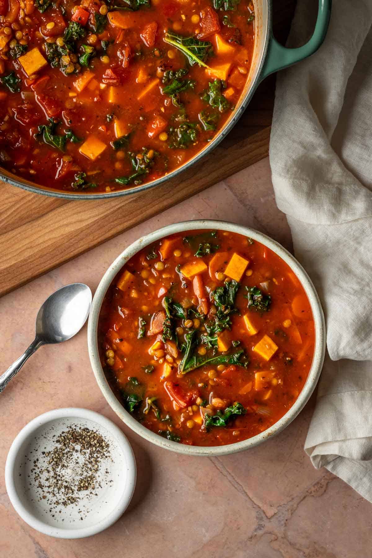 A large pot and a bowl of lentil vegetable soup.