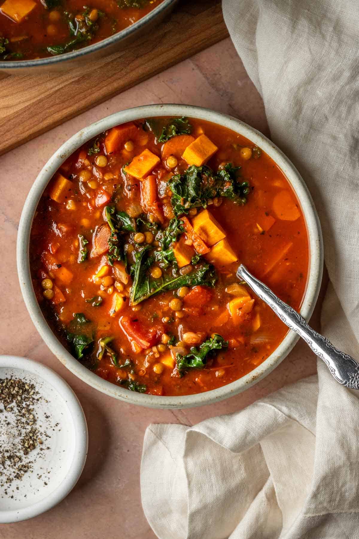 Lentil vegetable soup with kale in a bowl with a spoon.
