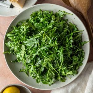 A bowl of arugula salad with parmesan cheese.