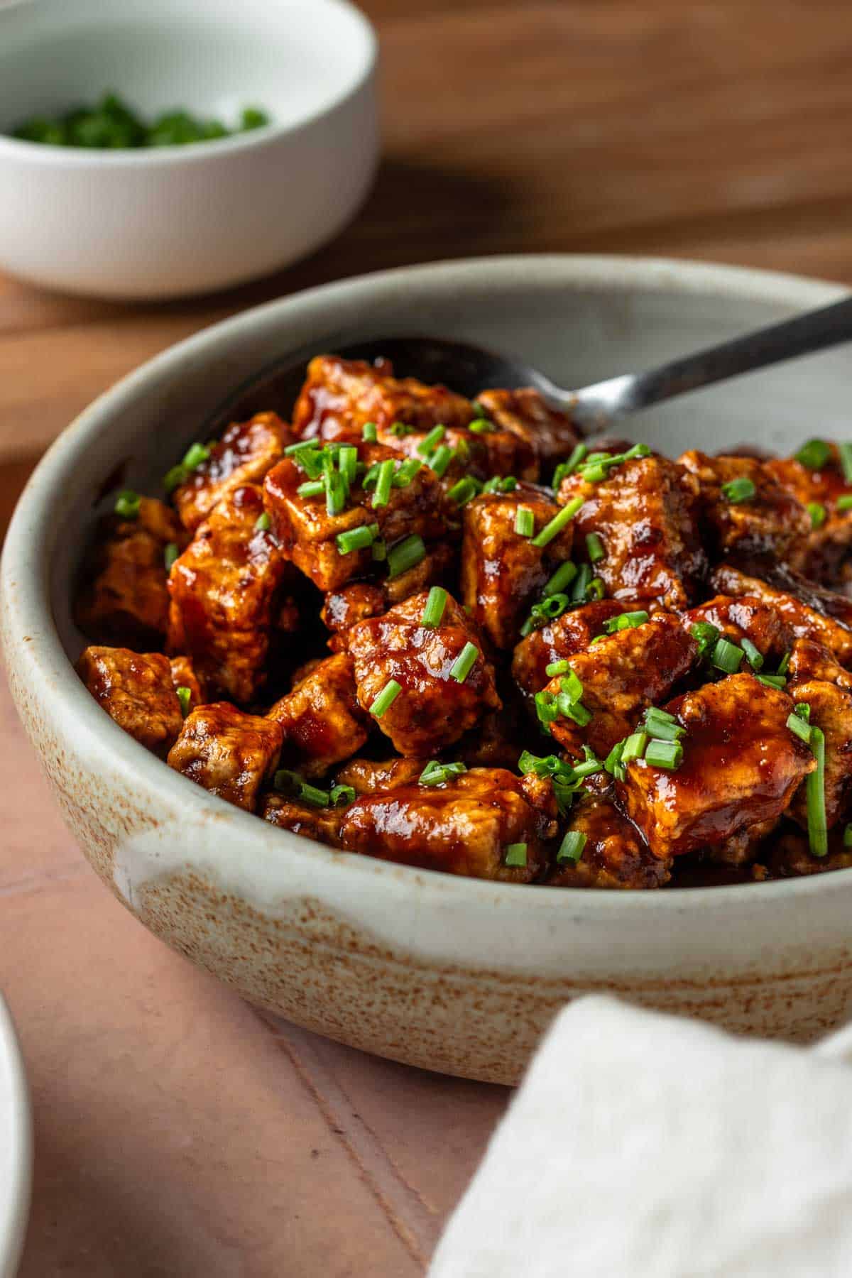 Crispy bbq tofu in bowl with a spoon.