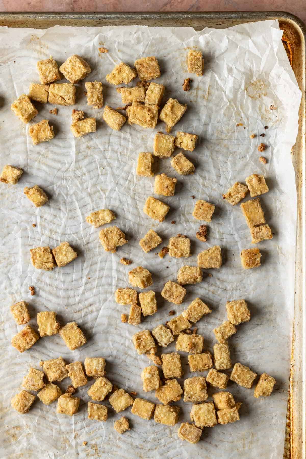 Crispy tofu on a baking sheet with parchment paper.