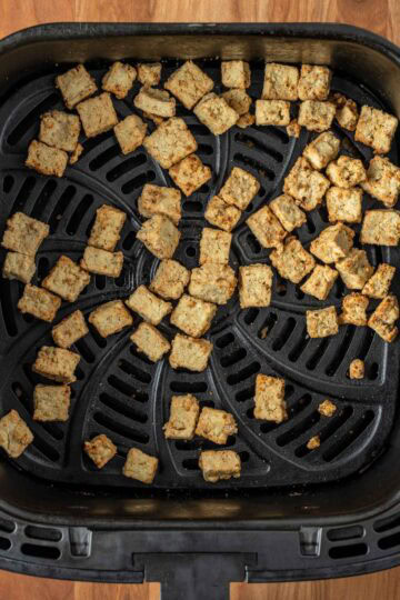 Crispy tofu cubes in the air fryer basket.