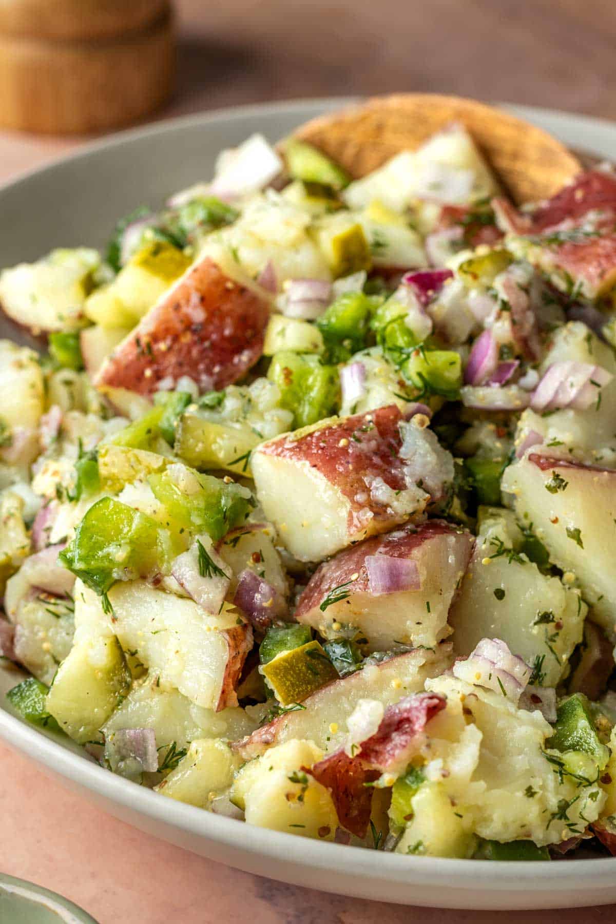 A large bowl of potato salad with dill pickles.