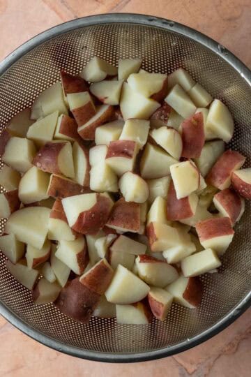 Boiled red skin potatoes in a strainer.